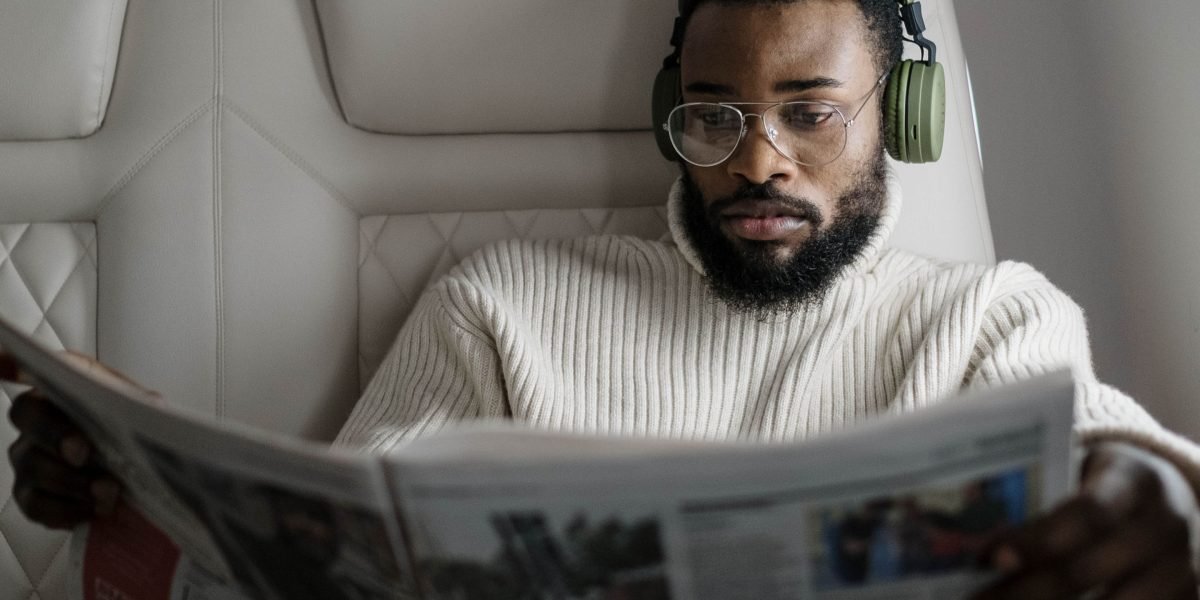 A person pausing to consider the information presented in a newspaper, reflecting on its trustworthiness.