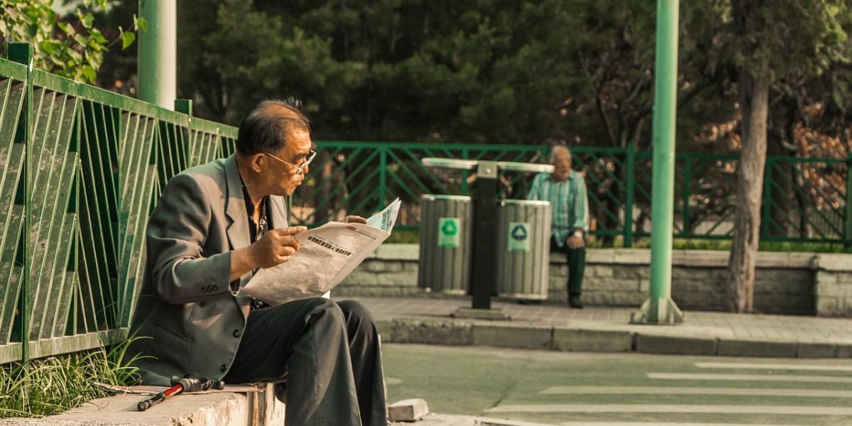 A person deeply engaged in reading an old newspaper, reflecting on its historical context.