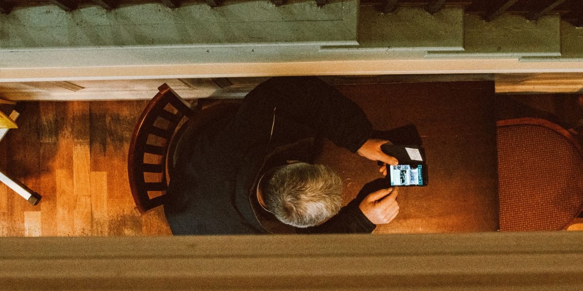 A person thoughtfully scrolling through a news app on their phone, reflecting on the content.