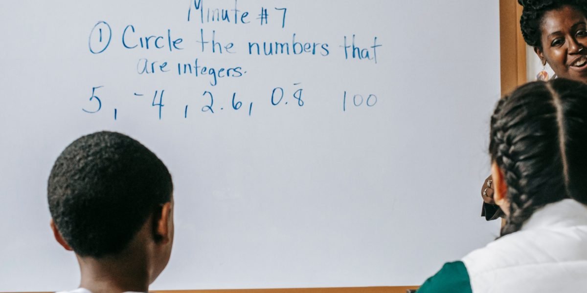 An educator interacting with students, demonstrating how to teach media literacy and critical thinking skills.
