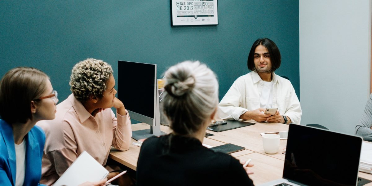 A group of professionals in a meeting setting, discussing business strategy or financial outcomes.