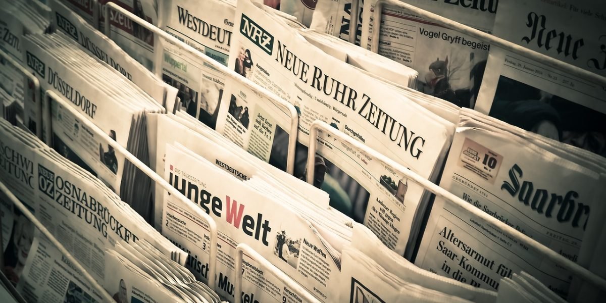 A person engaged in reading a local newspaper, connecting with community events and news.