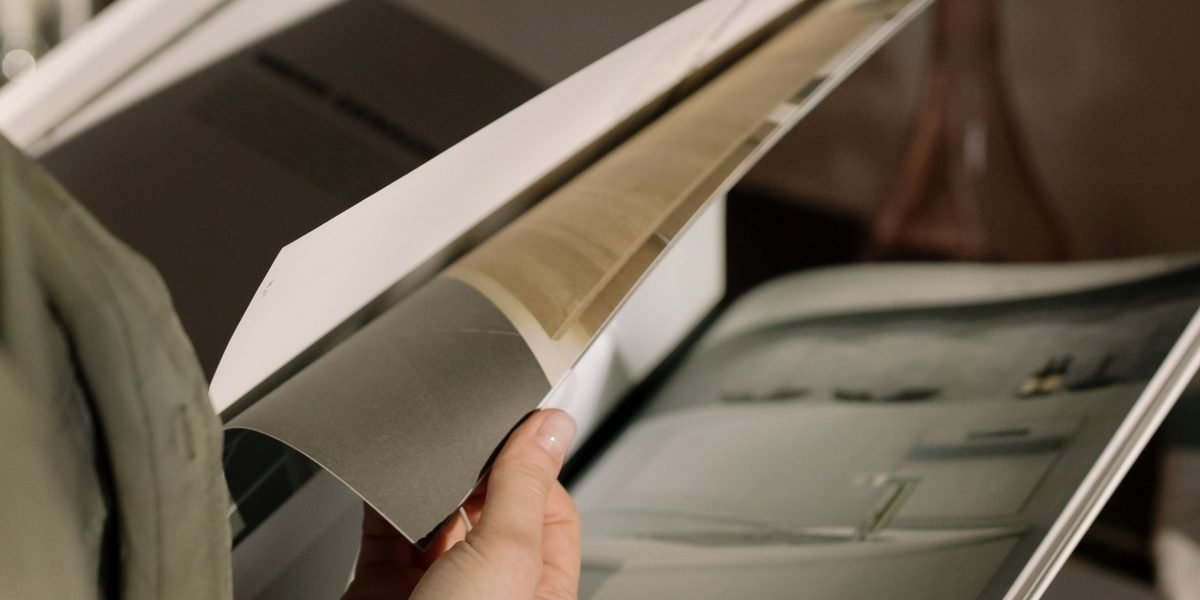 A person deeply engrossed in reading a physical print magazine, demonstrating deep focus and concentration.