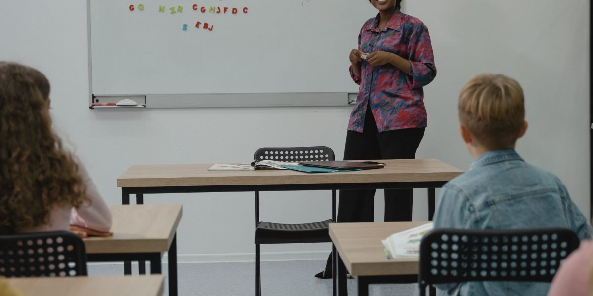 An educator explains concepts of media literacy and bias detection to students using a whiteboard in a classroom setting.